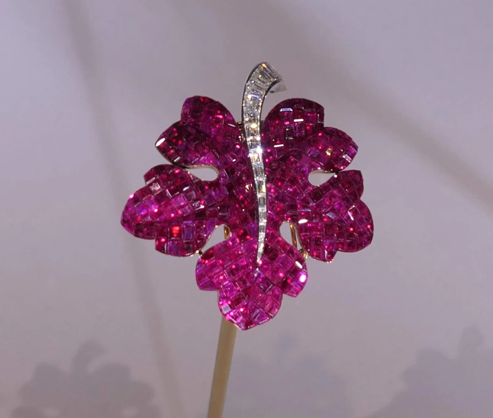 Van Cleef & Arpels mystery-set ruby leaf clip with a curved baguette-diamond vein