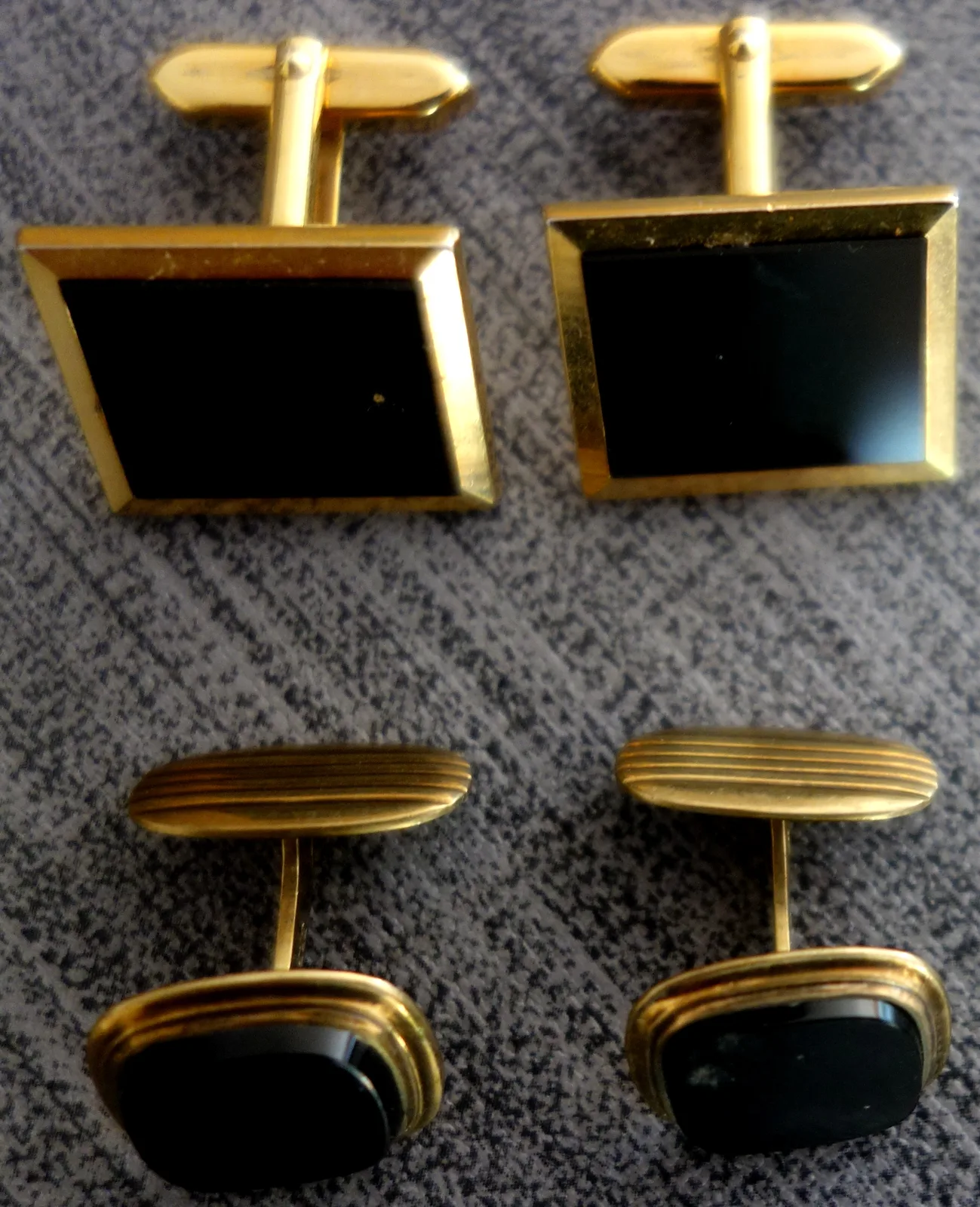 Pair of gold cufflinks, each with a faceted black onyx, on a light ground