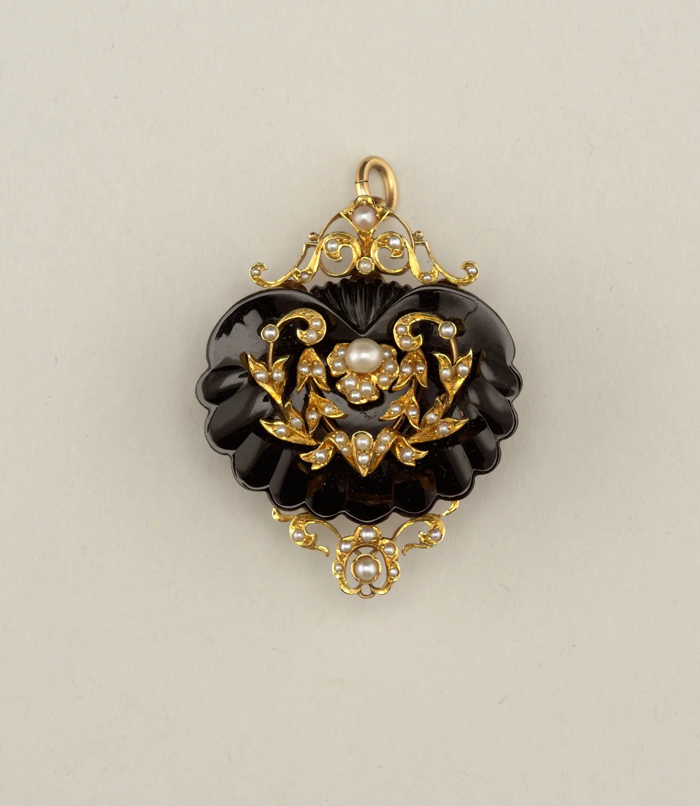 Museum catalog still of an 1860s gold brooch framing an oval onyx with a classical profile