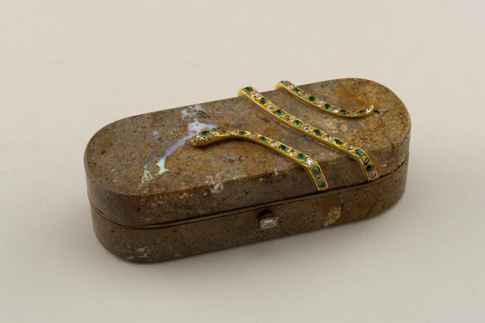 Oblong box cut from dark opal matrix with blue and green veins and a gold serpent set with emeralds and diamonds