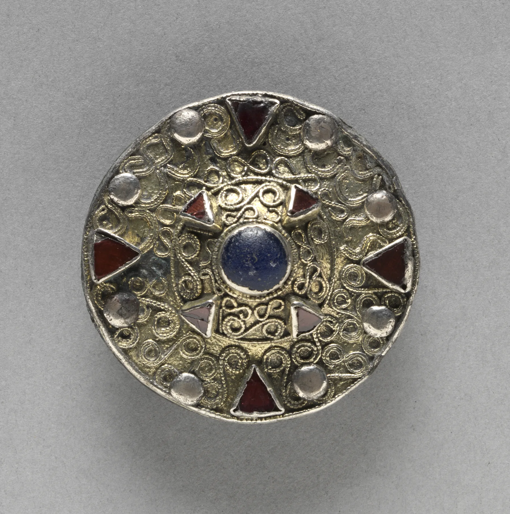 Late Merovingian gilt-silver disk brooch with a central boss and a ring of filigree around glass and almandine