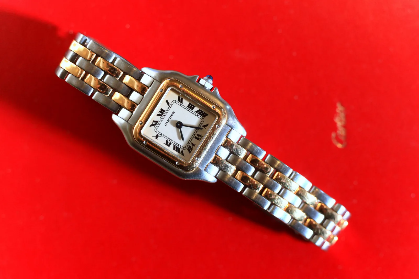 Cartier Panthère two-tone watch with a square steel-and-gold case and brick-link bracelet, shown in a red Cartier box