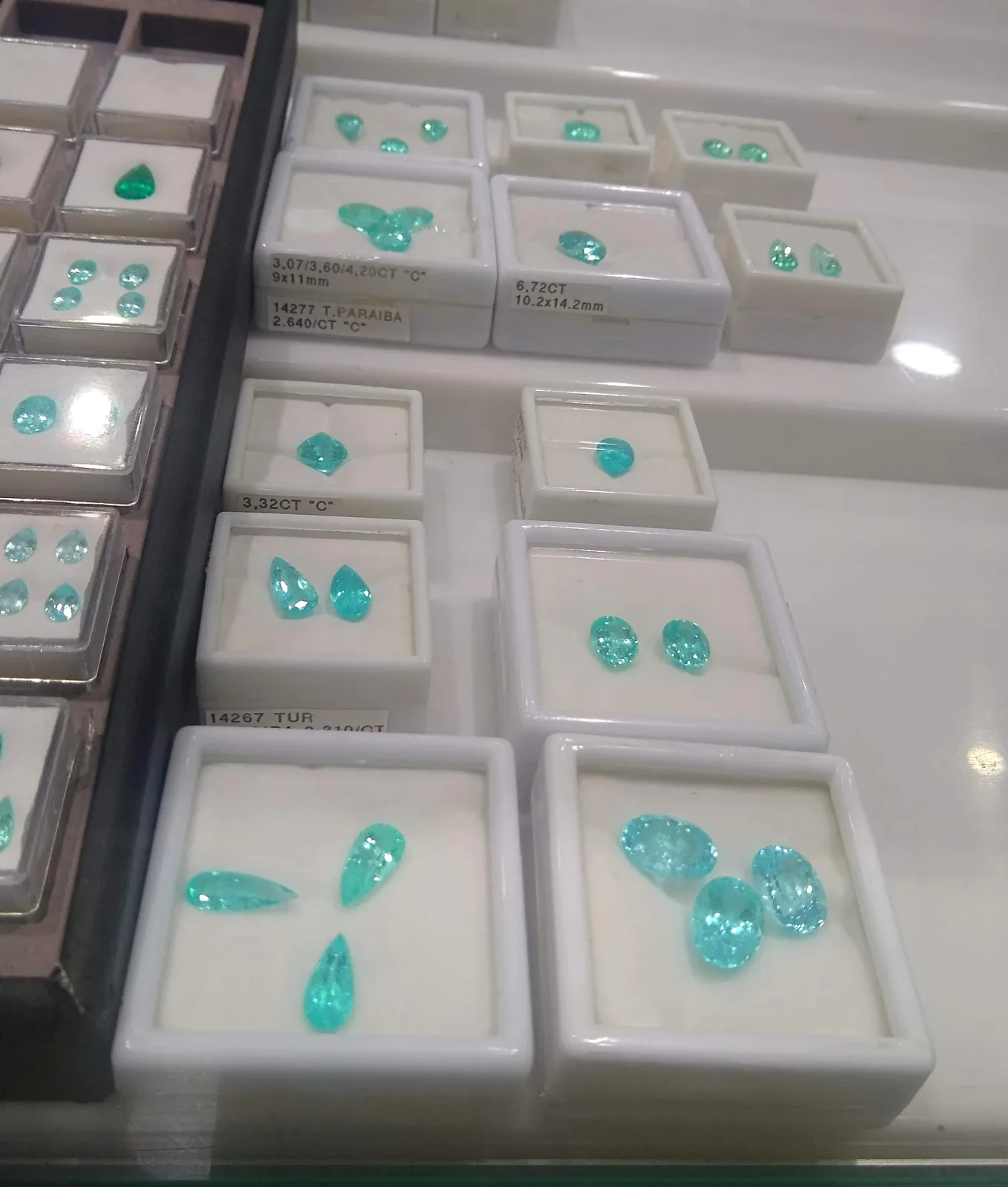 Assortment of faceted Paraíba tourmalines from Brazil, neon blue and blue-green, on a dark ground