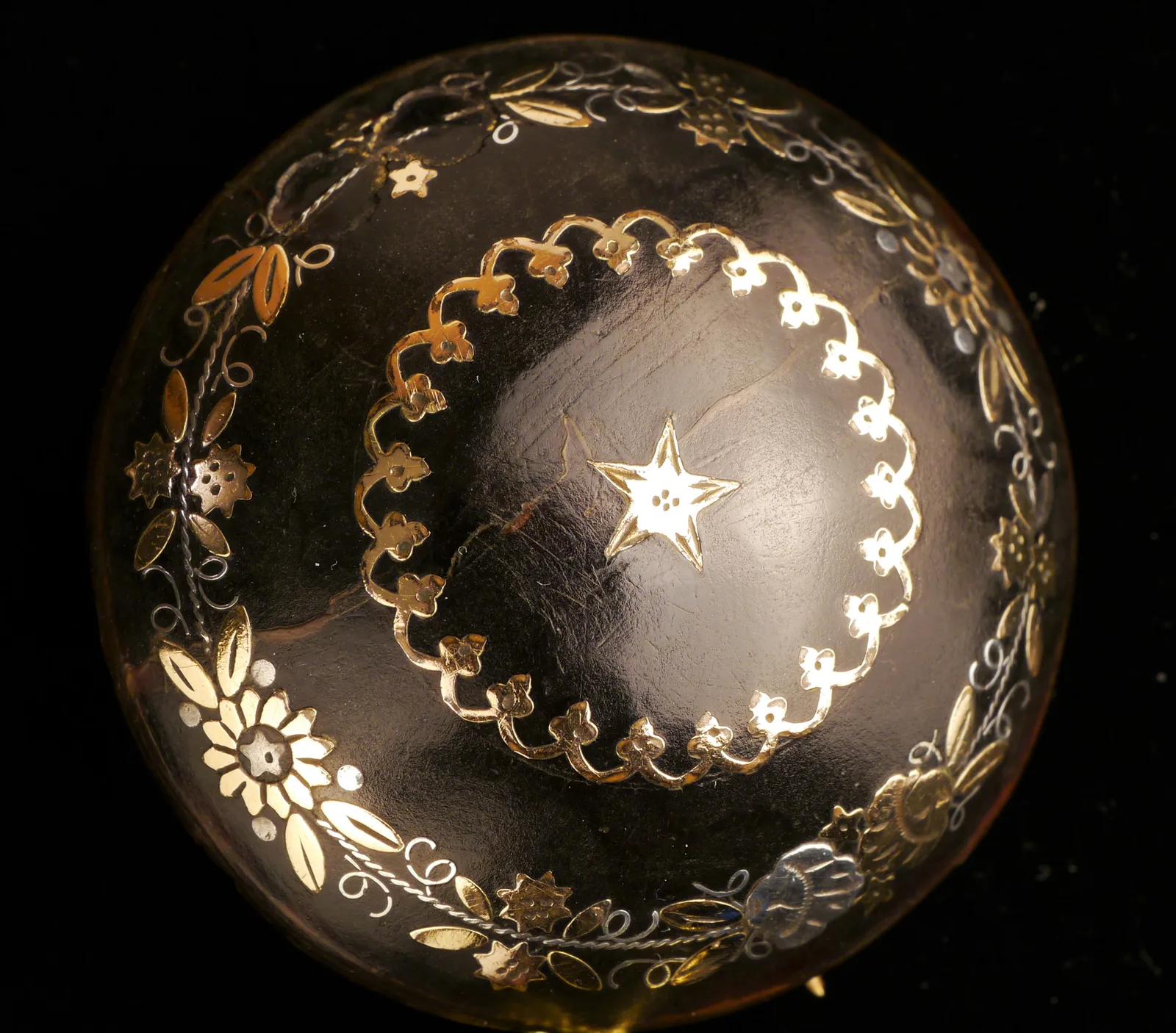 A round Victorian tortoiseshell brooch with a central cluster of gold and silver points and a scalloped edge
