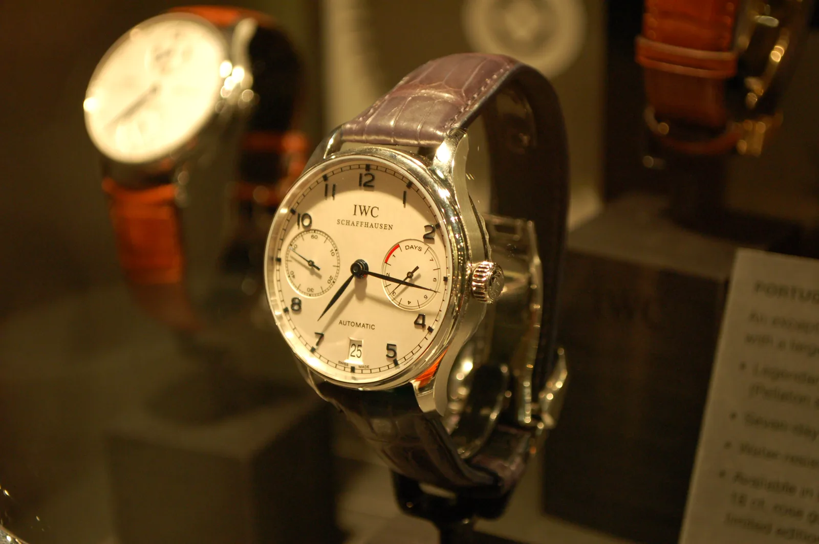 IWC Portuguese Automatic with a white dial, black Arabic numerals, a minute track, leaf hands, a date, and a small seconds, shown off the wrist on a white ground