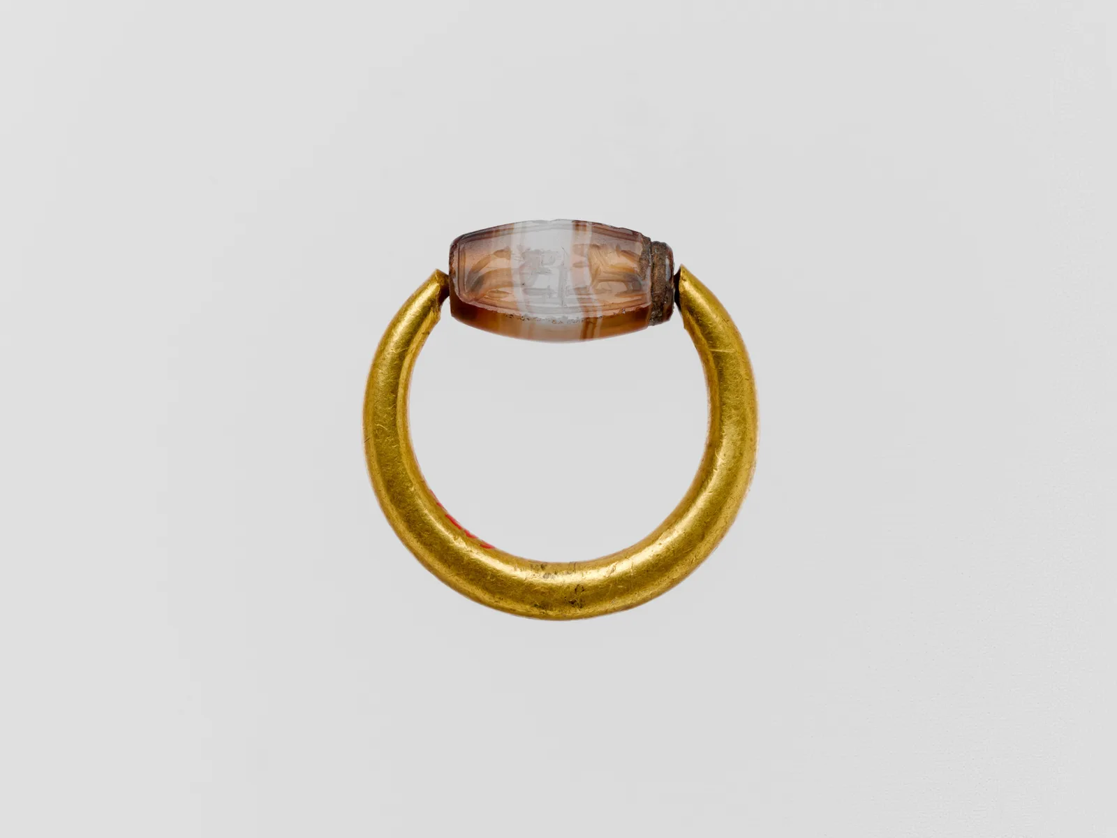 Cypriot or Phoenician gold hoop with a banded agate scaraboid set to swivel between the open ends of the ring