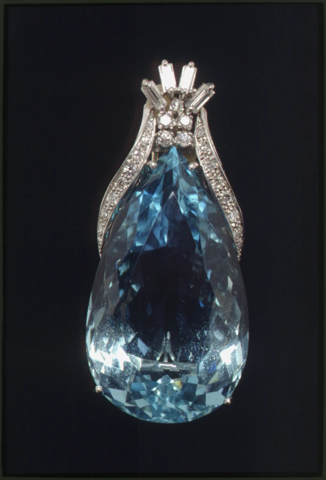 Teardrop aquamarine held in a platinum-wire setting, with diamond clusters and white-gold ribbons, made to be worn as a brooch or pendant