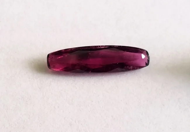 An oval rubellite of 1.63 carats, deep pink toward ruby, on a white ground