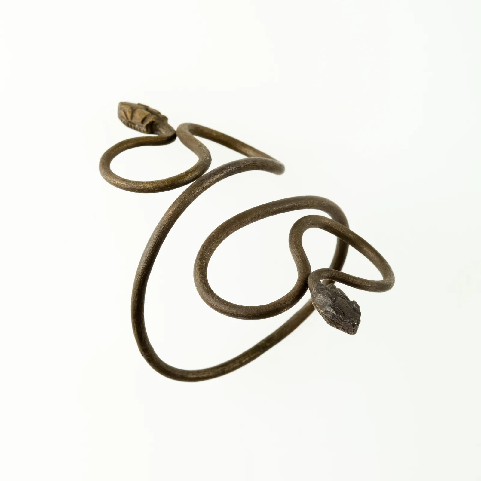 Ptolemaic or Roman silver bracelet drawn as a thin snake with a head at each end, coiled as one continuous line