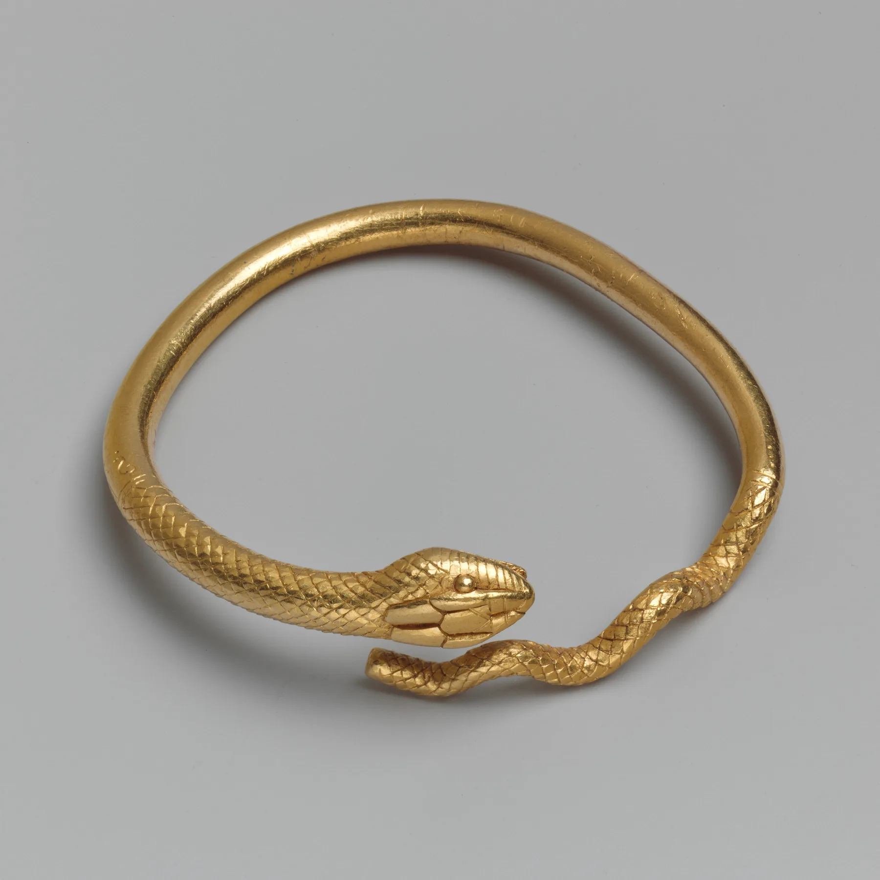 Ptolemaic gold bracelet shaped as a single snake with a detailed head and tapering scaled tail