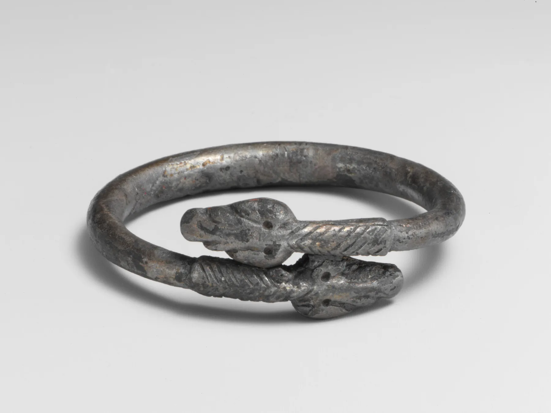 Roman silver bypass bracelet formed as a snake with two stylized heads overlapping on a thick hoop