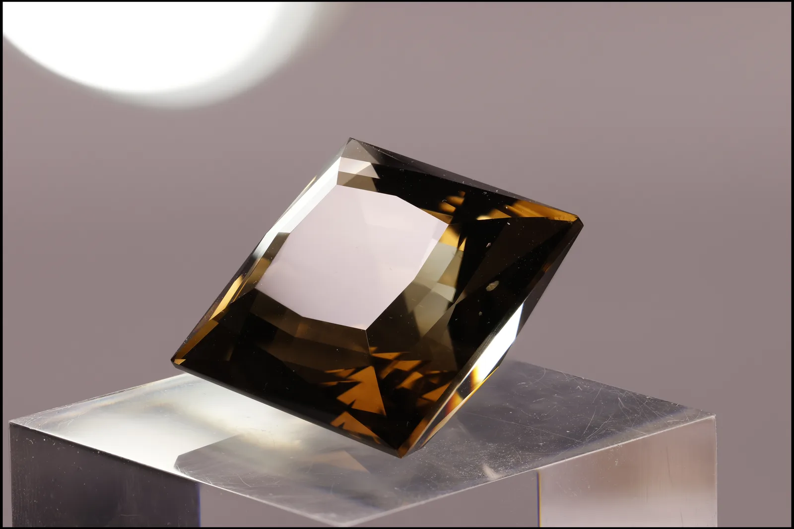 A faceted smoky quartz from South Bohemia, translucent tobacco brown, on a pale ground