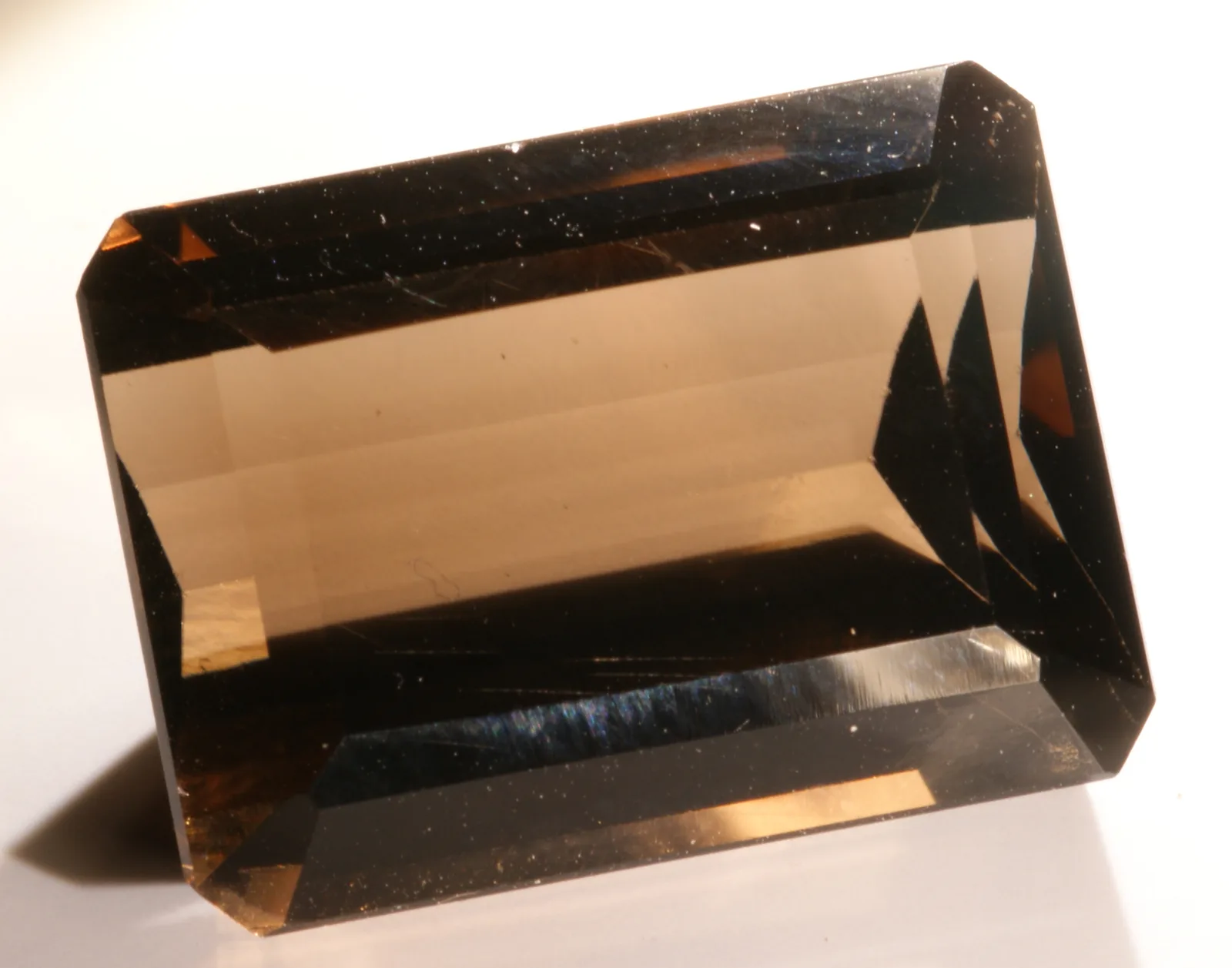 A small faceted smoky quartz from Minas Gerais, a lighter cognac brown, on a pale ground