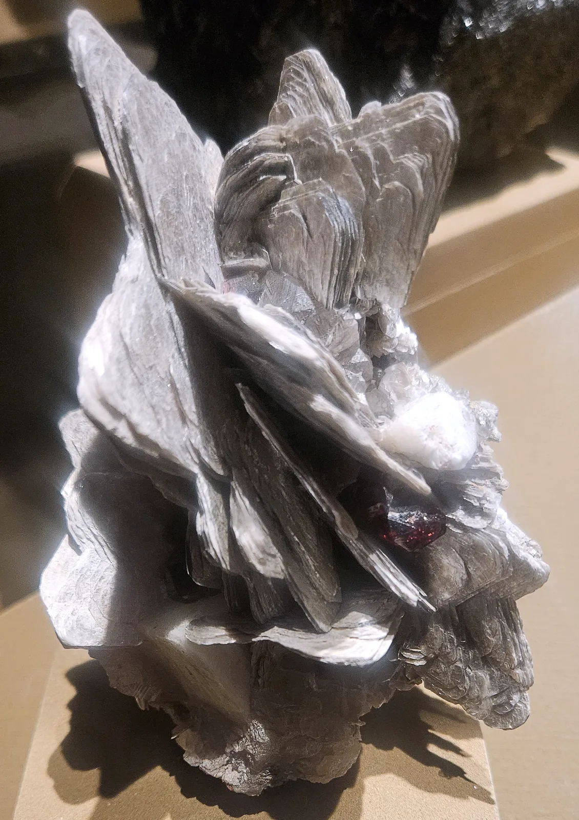 Orange spessartine in books of silvery muscovite, a museum specimen from Pakistan on a light ground