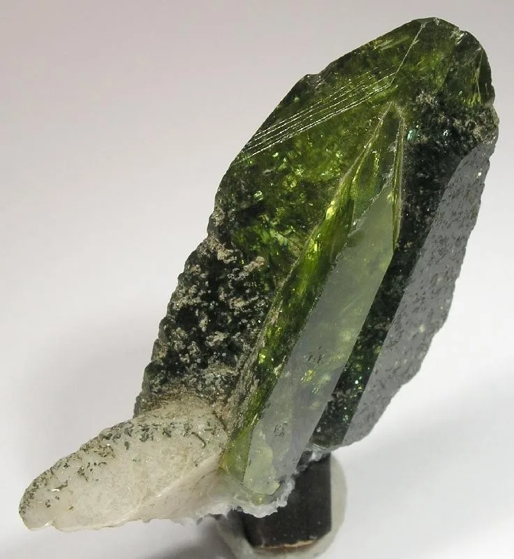 A twinned titanite crystal, golden and glassy, with a paler crystal grown against it, on a white ground