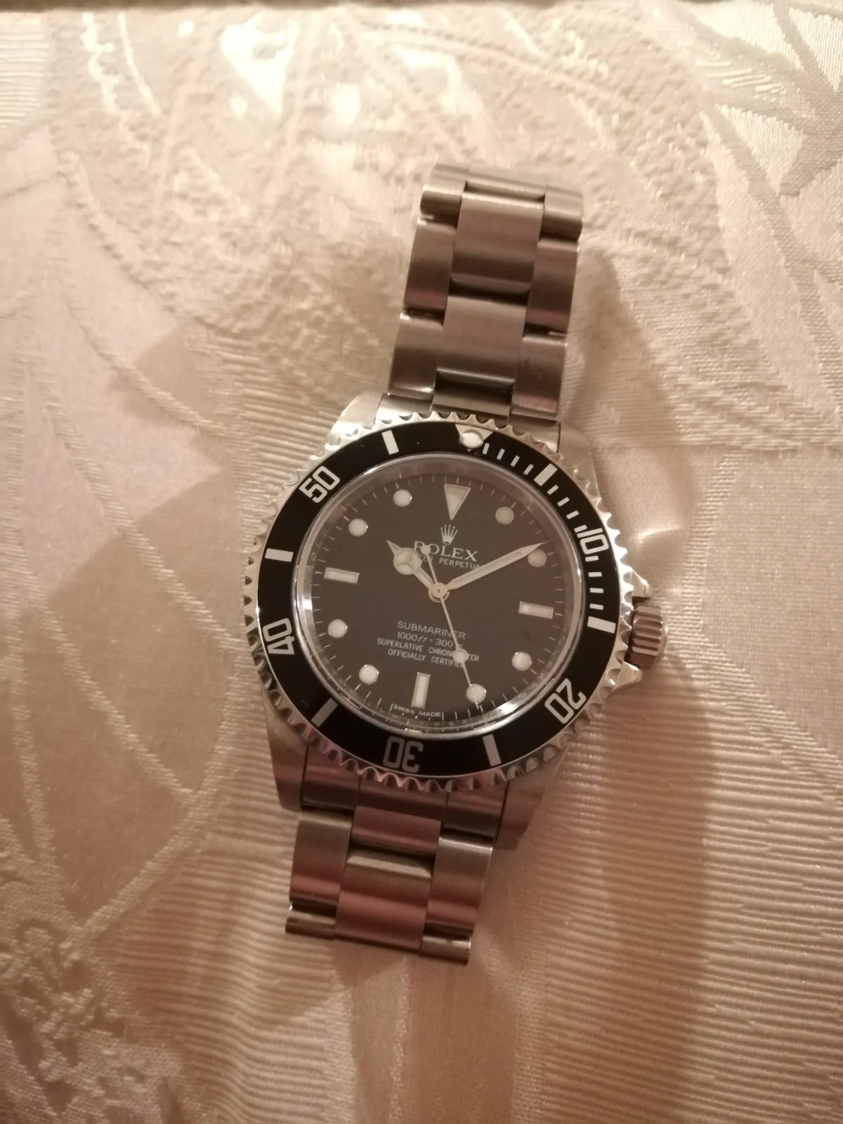 Rolex Submariner reference 14060M with a black dial and black bezel, no date window, shown off the wrist on a white ground