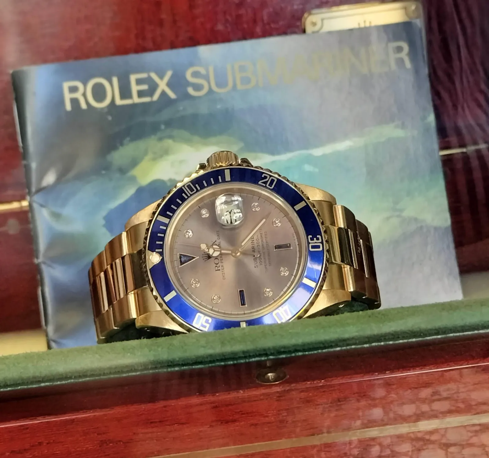 Yellow-gold Rolex Submariner reference 16618 with a Sultan dial and a date window, shown off the wrist on a white ground