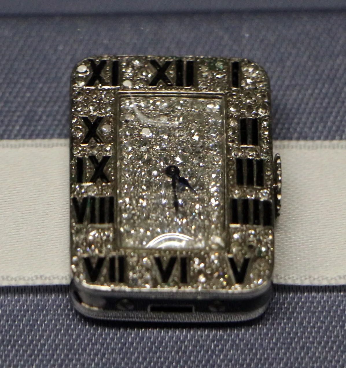 Cartier diamond clip watch with Roman numerals in a pavé frame on a cream ribbon