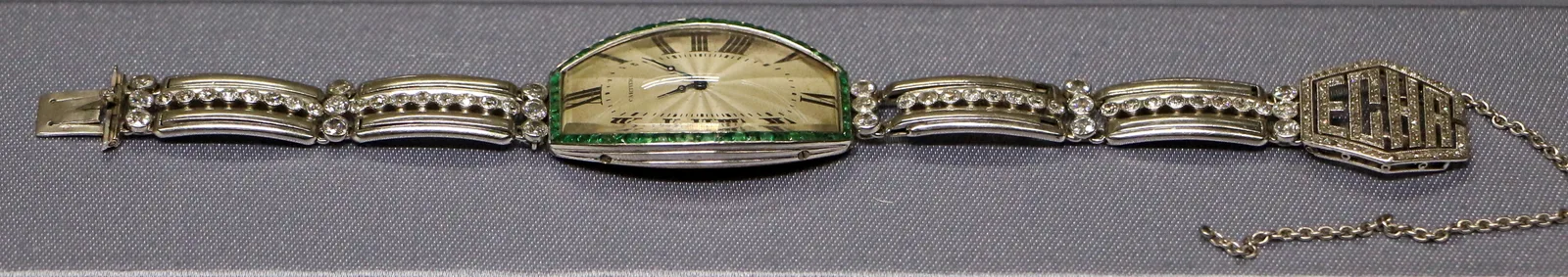 Cartier platinum jewelry watch with a cream dial, emerald rim, and diamond bracelet, c. 1919–25