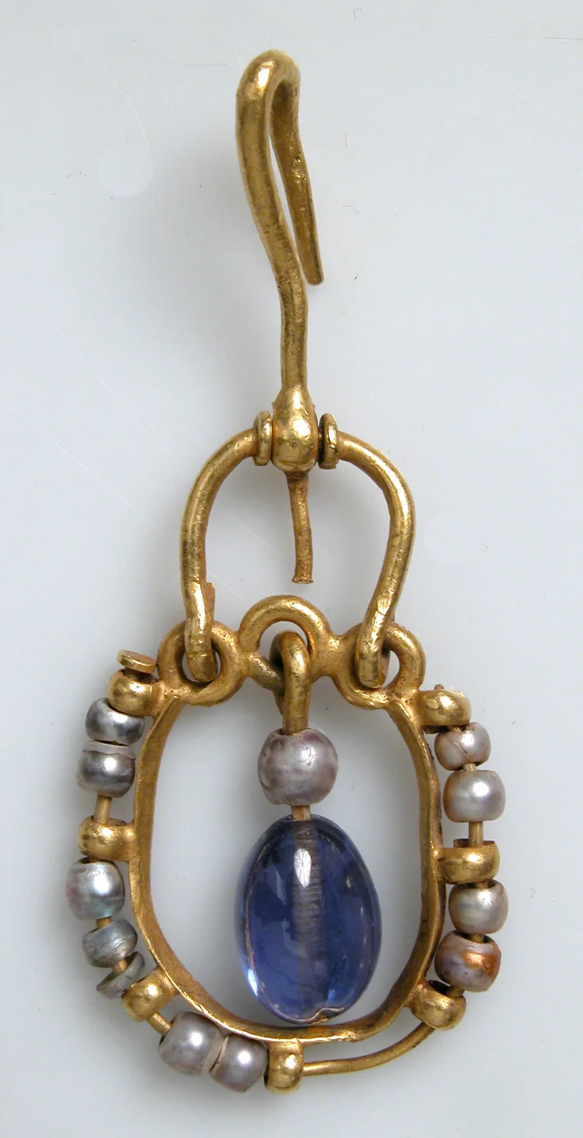 Byzantine gold earring with an oval hoop of pearls around a hanging violet-blue sapphire drop and a long gold hook