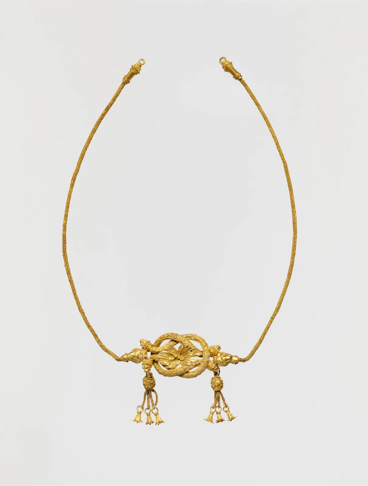 Hellenistic gold fillet, a slender woven chain whose center is a Herakles knot with lion-head terminals and hanging gold tassels