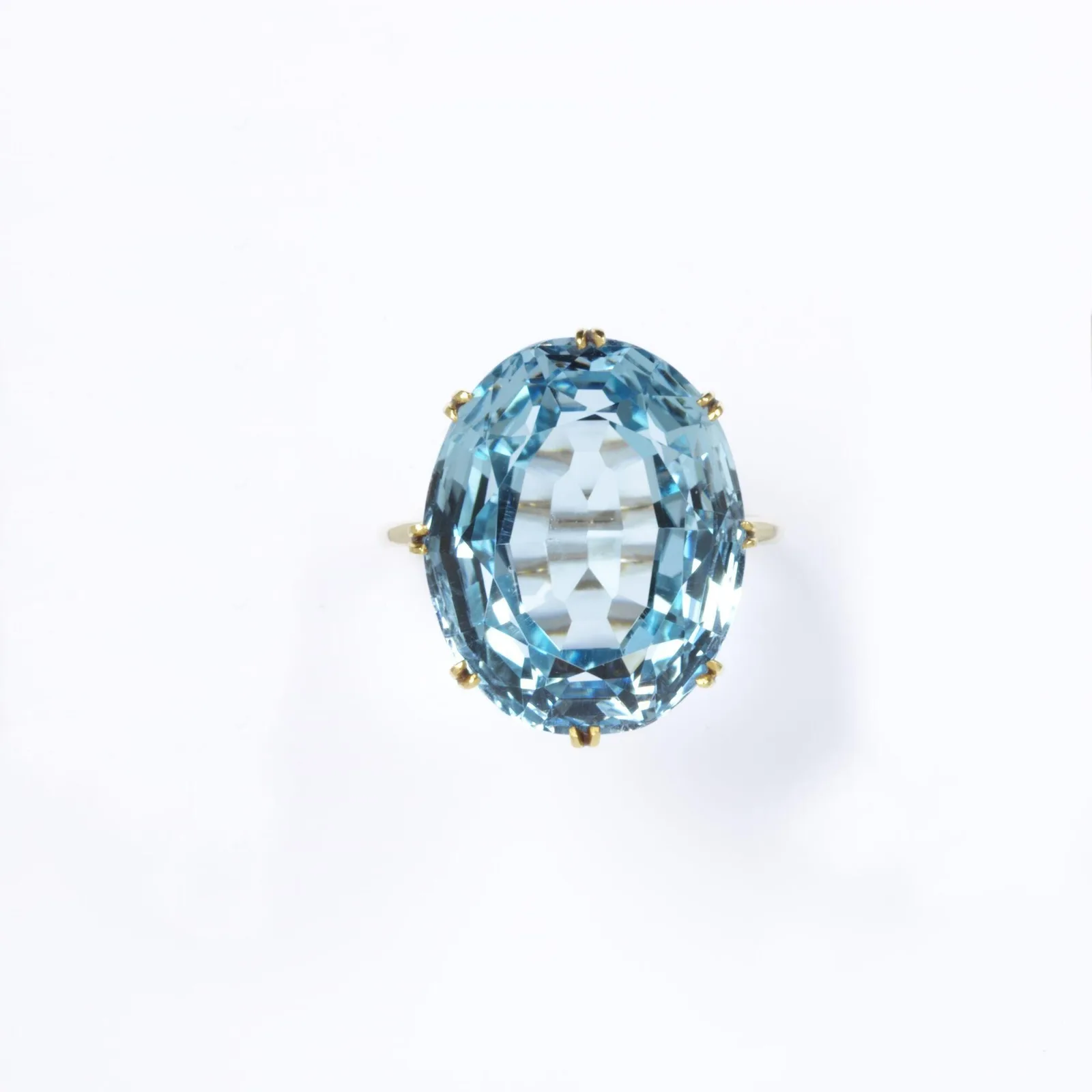 Oval sea-blue topaz in a gold coronet mount, the stone already a cool bright light