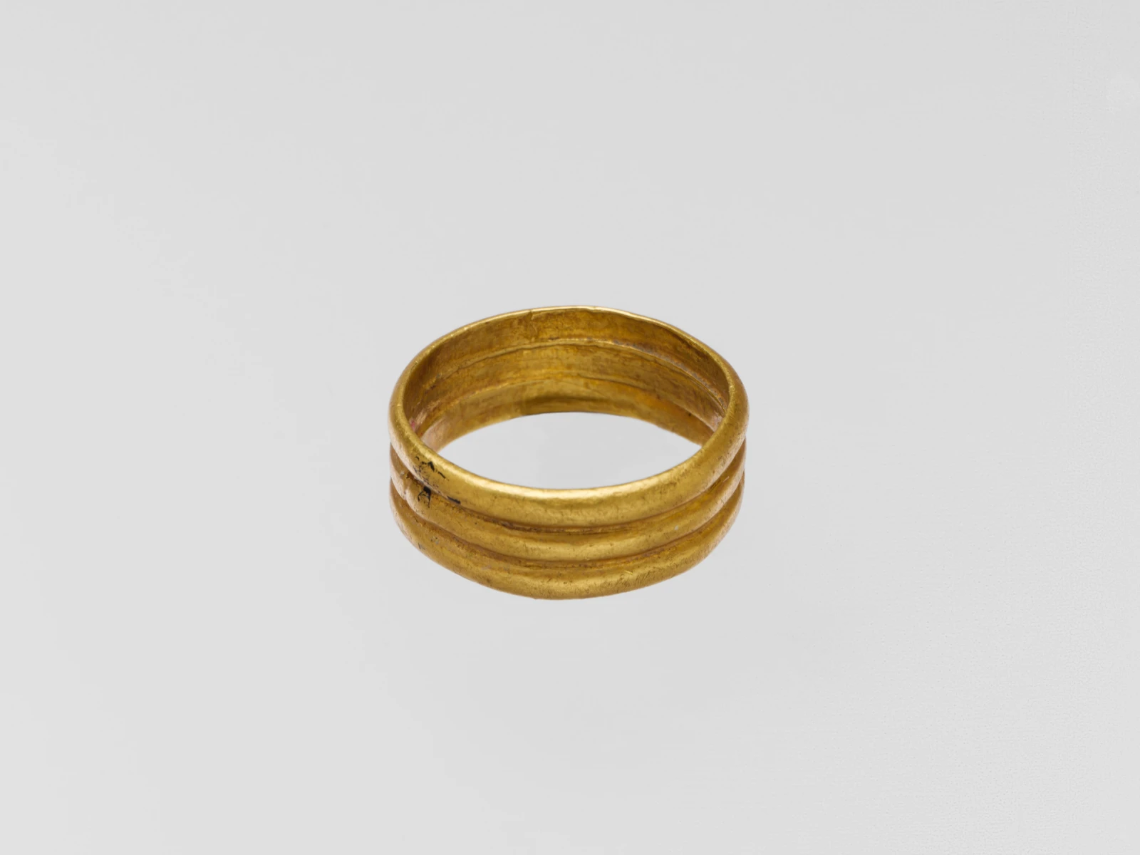 Ancient gold finger ring formed as three parallel rounded ribs around a single hoop