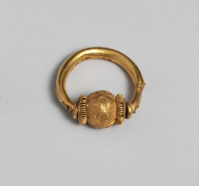 Etruscan gold ring with a thick hoop and a granulated spherical bead that can revolve between coiled-wire collars
