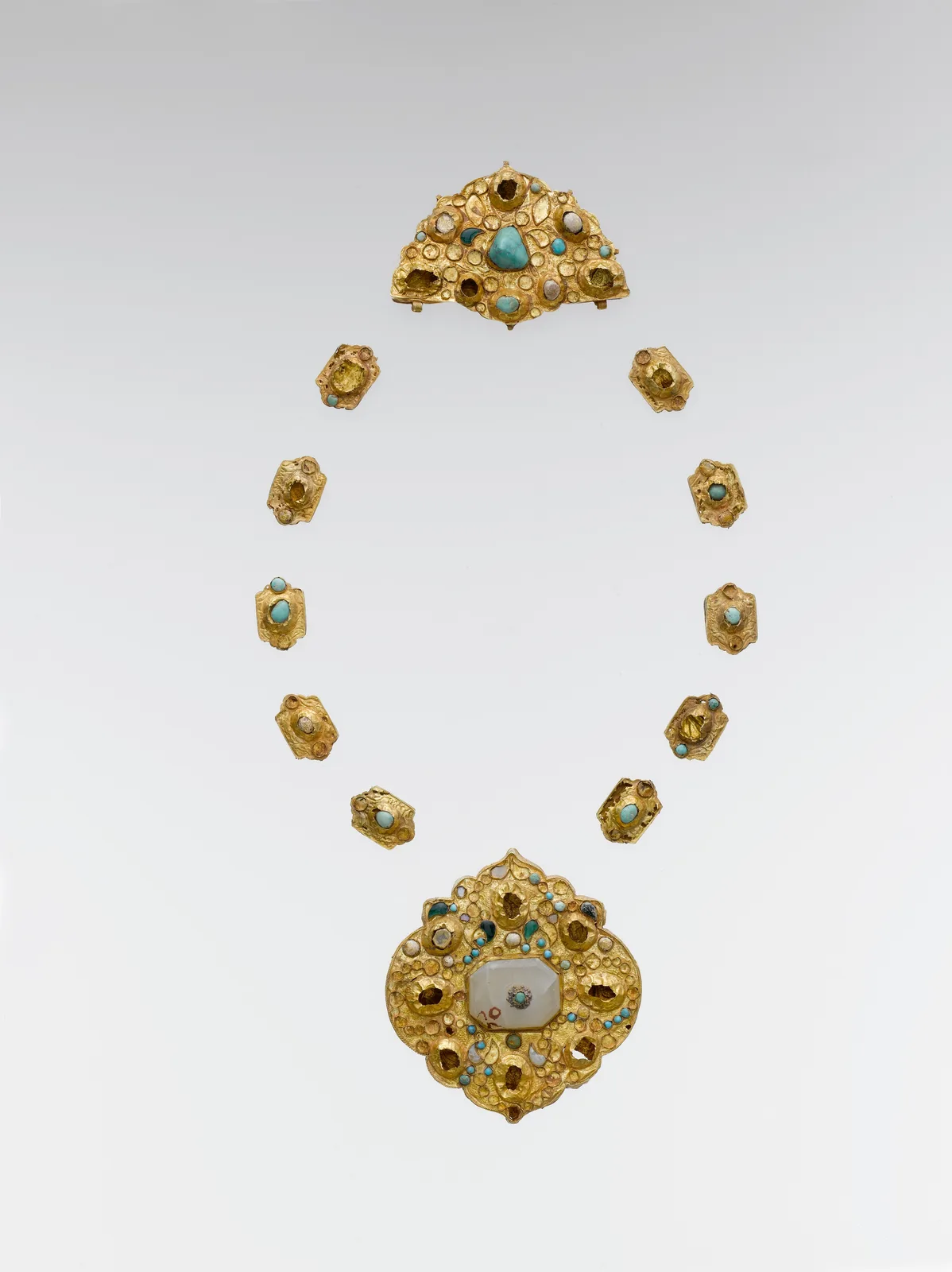 Late medieval gold necklace elements from Iran or Central Asia: a large medallion, a half-medallion, and a row of small cartouches set with turquoise and gray stone